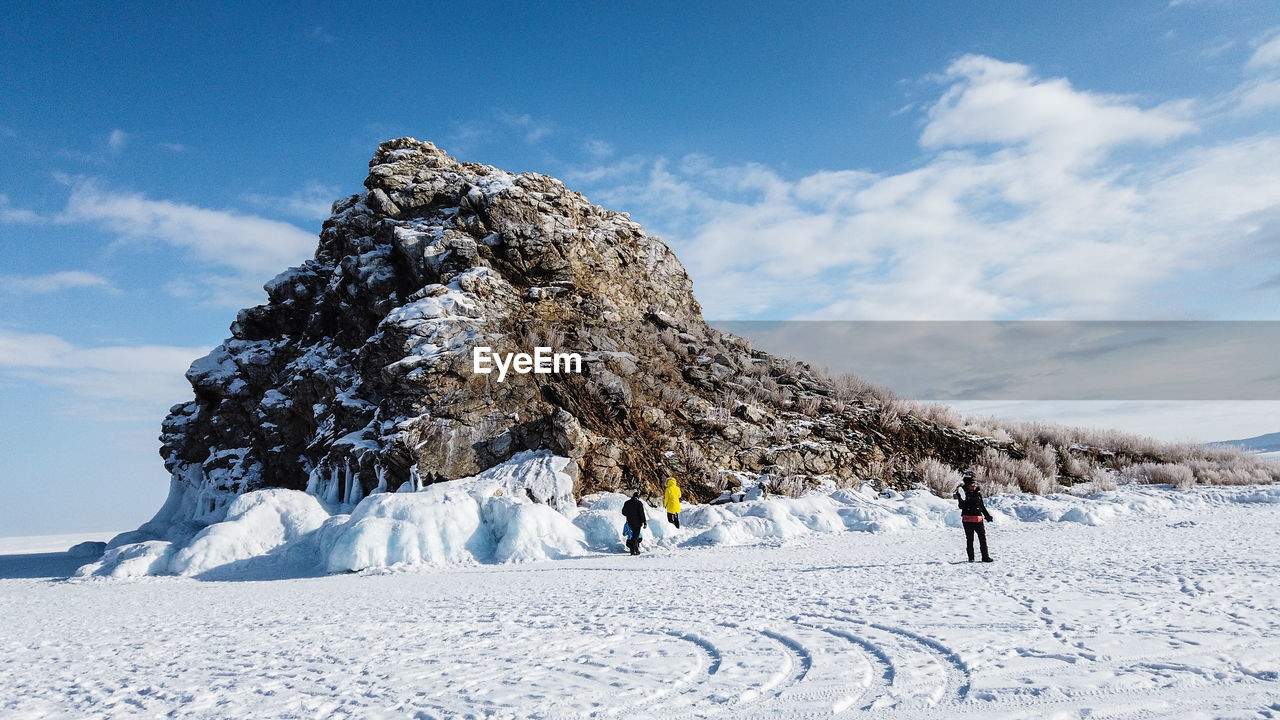 PEOPLE ON SNOW COVERED FIELD AGAINST SKY DURING WINTER