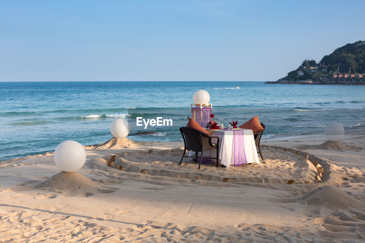 PEOPLE SITTING ON SHORE AT BEACH