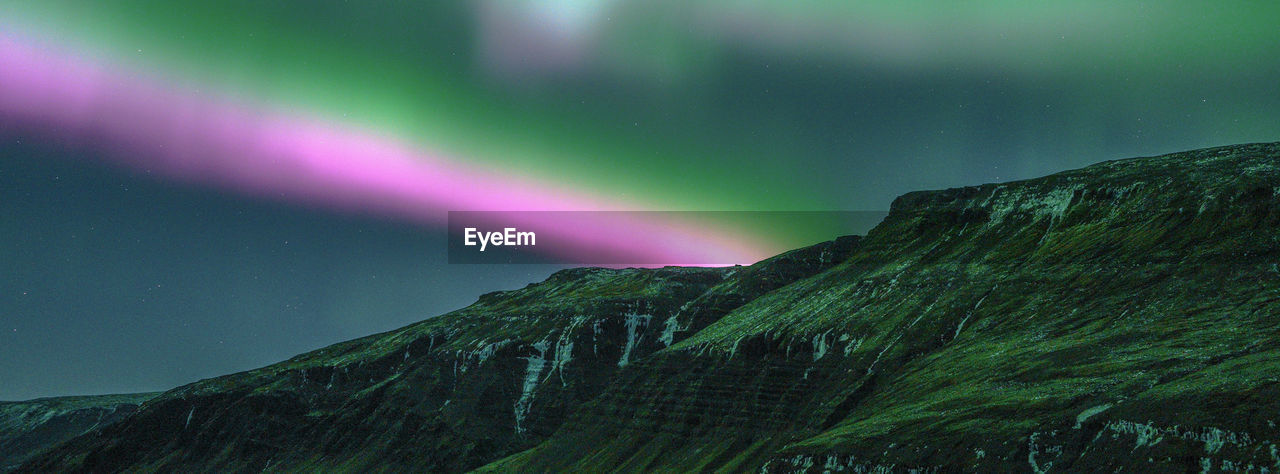 Low angle view of aurora over mountain against sky
