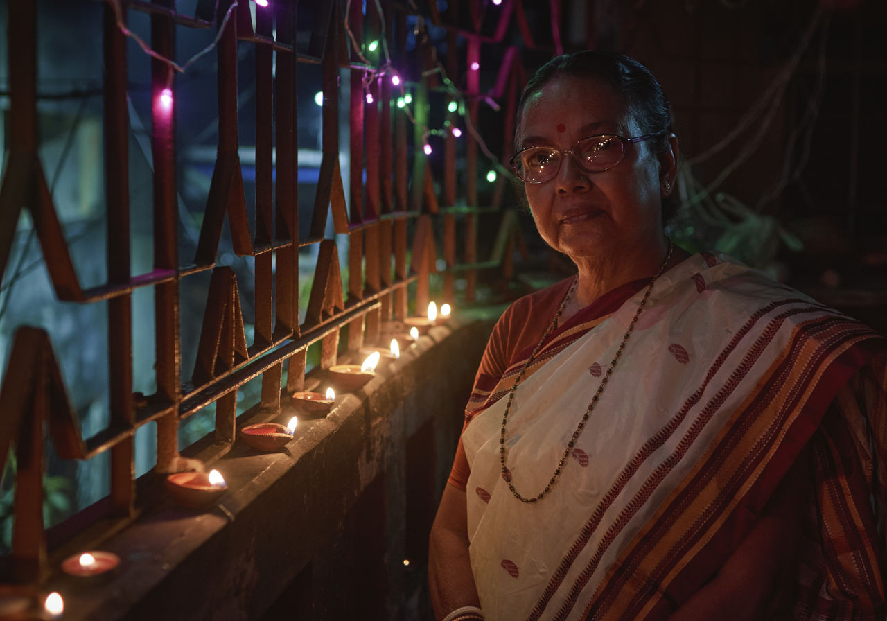 A hindu woman decorating her home with diyas on the evening of diwali and kali puja.