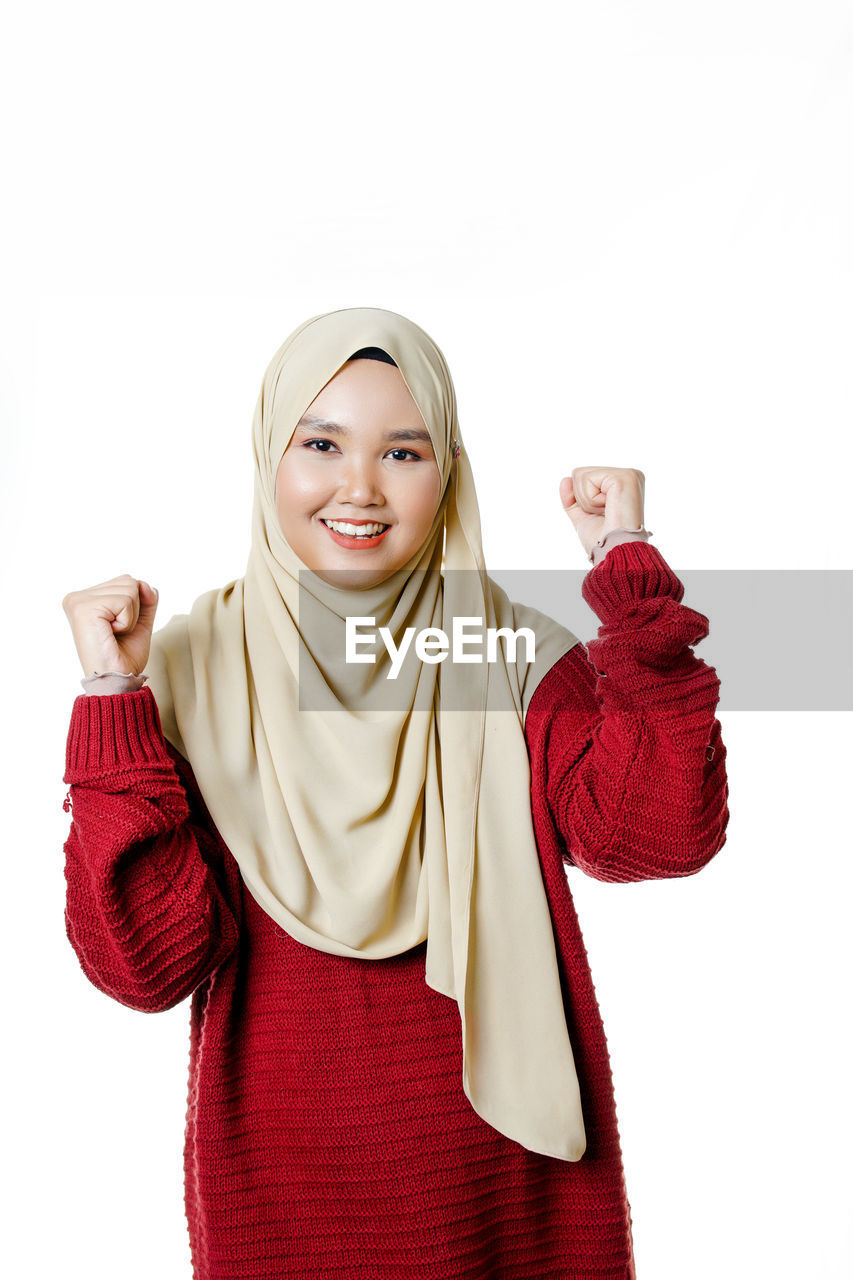 PORTRAIT OF SMILING YOUNG WOMAN AGAINST RED BACKGROUND