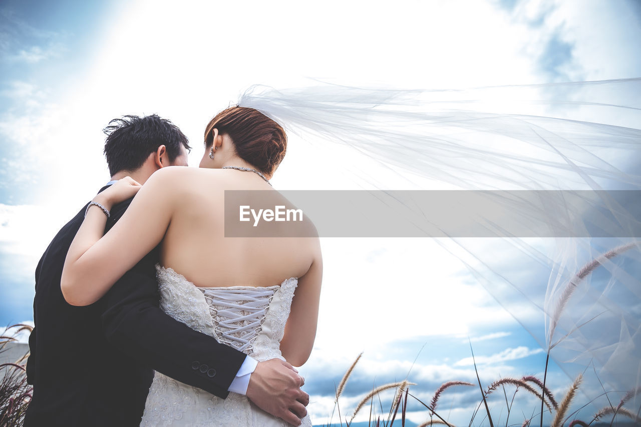 REAR VIEW OF COUPLE WALKING AGAINST THE SKY