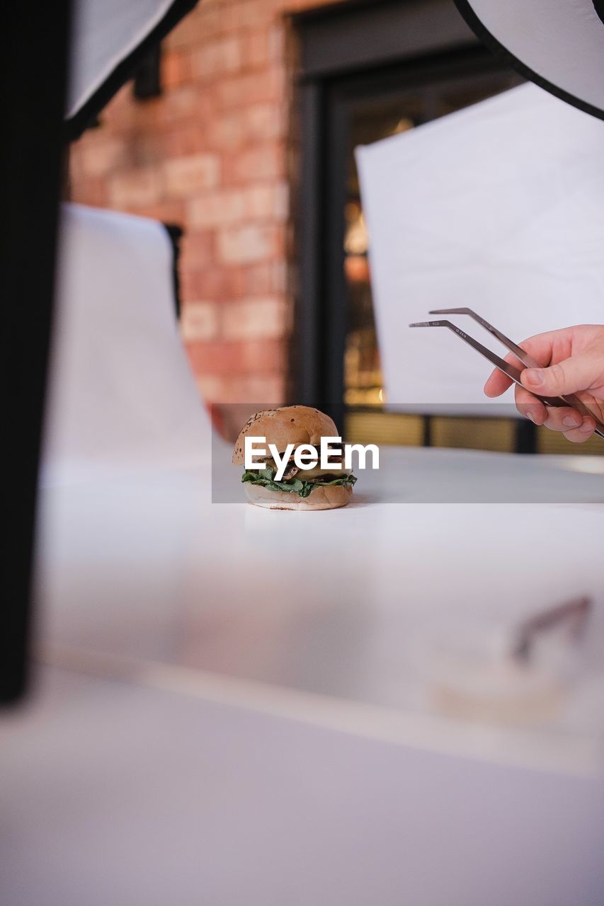 Close-up of hand preparing a burger