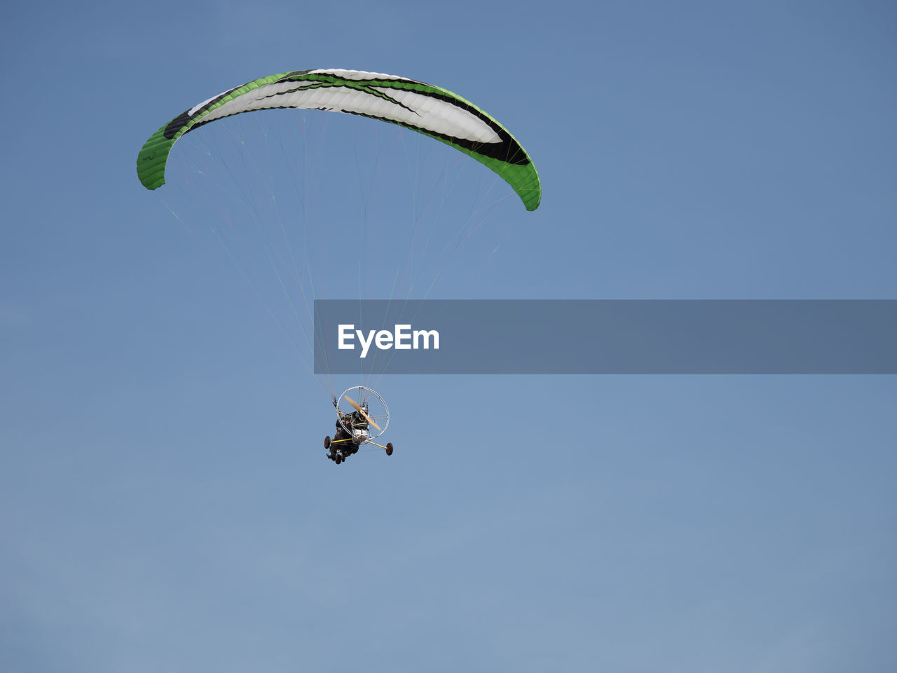 Low angle view of person motor paragliding in clear sky