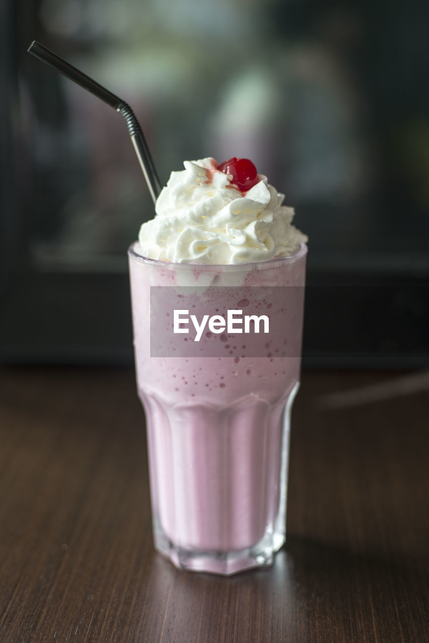 Drink with whipped cream in glass on table