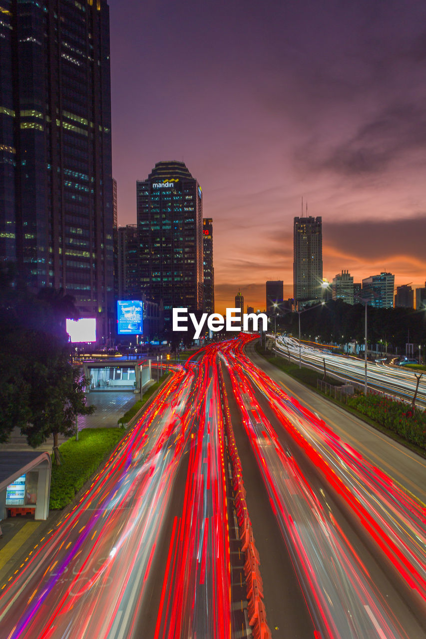 architecture, city, building exterior, built structure, long exposure, illuminated, light trail, night, motion, office building exterior, transportation, traffic, building, skyscraper, speed, street, cityscape, metropolitan area, road, city life, sky, landscape, urban skyline, city street, skyline, blurred motion, evening, tail light, downtown district, dusk, residential district, nature, urban area, travel destinations, highway, mode of transportation, multi colored, light, office, red, metropolis, no people, lighting equipment, business, horizon, travel, sunset, outdoors, business finance and industry, motor vehicle, infrastructure, street light, car, high angle view, downtown, twilight
