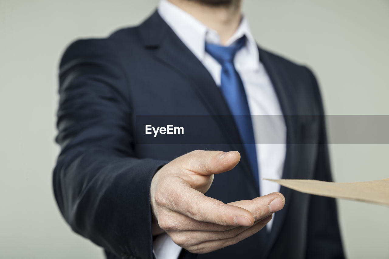 MIDSECTION OF MAN HOLDING CAMERA WHILE STANDING IN KITCHEN