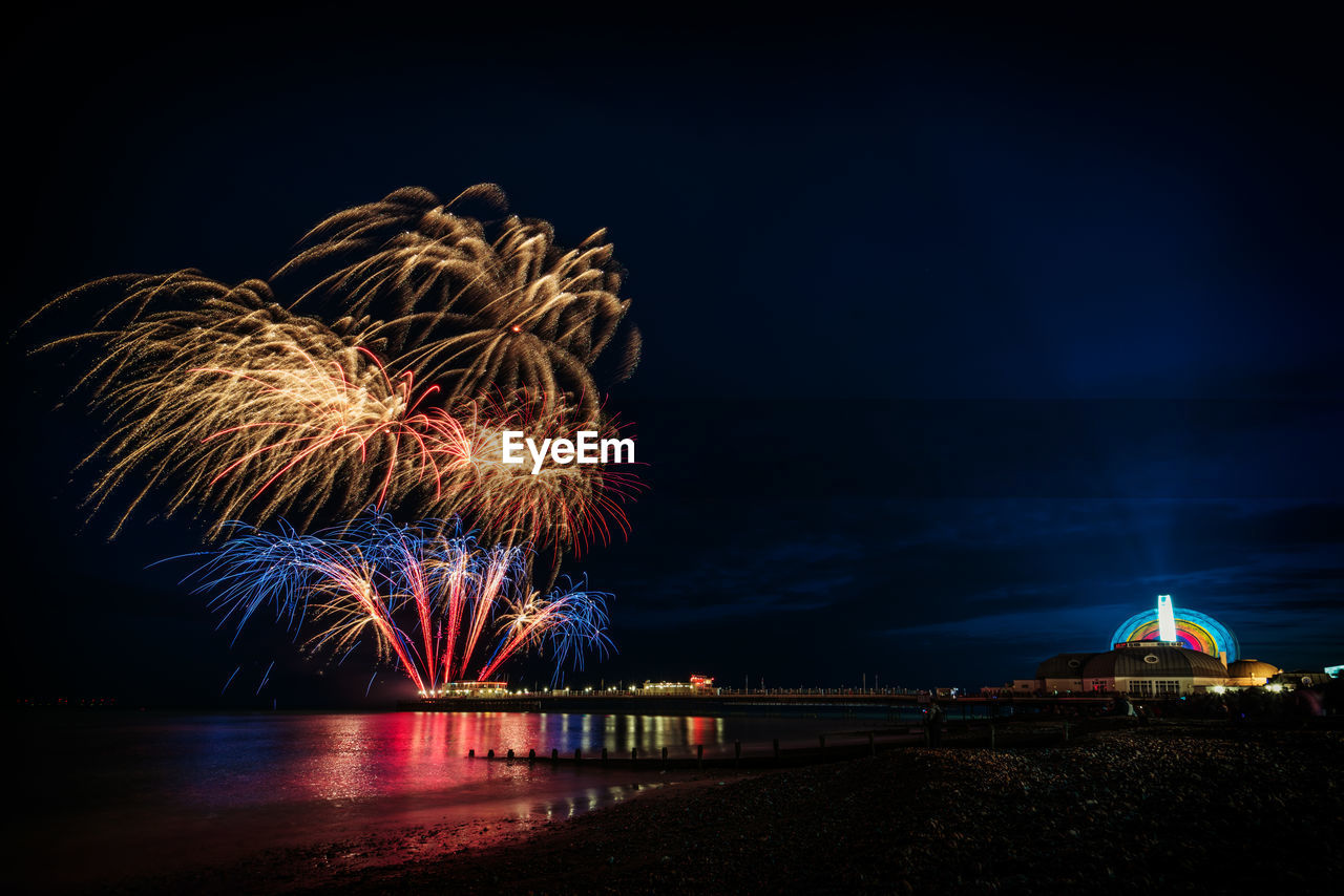 Firework display over river against sky at night