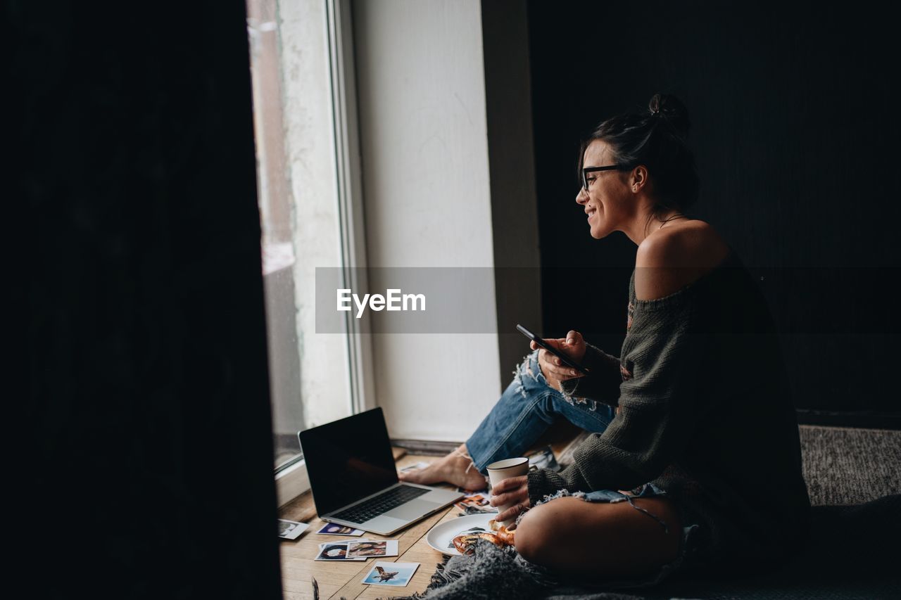 Woman using mobile phone while siting at home