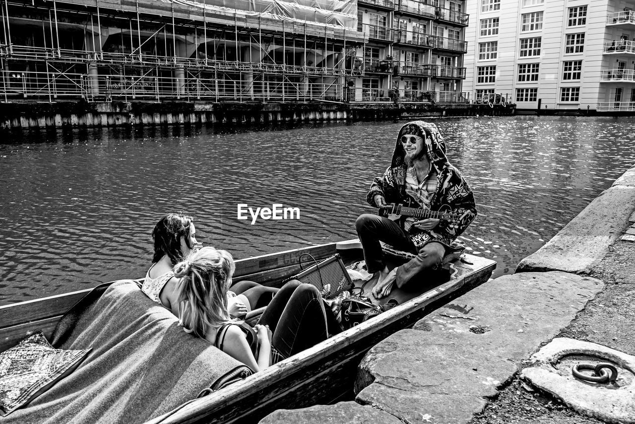 REAR VIEW OF PEOPLE SITTING IN RIVER