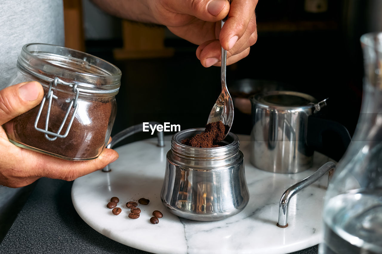 Man preparing classic italian coffee in the mocha, filling funnel of a moka pot with ground coffee.