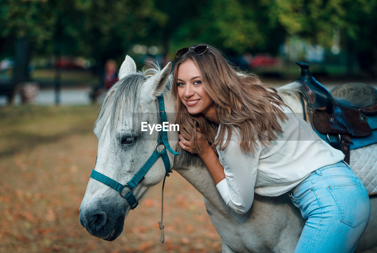 Portrait of woman standing by horse outdoors