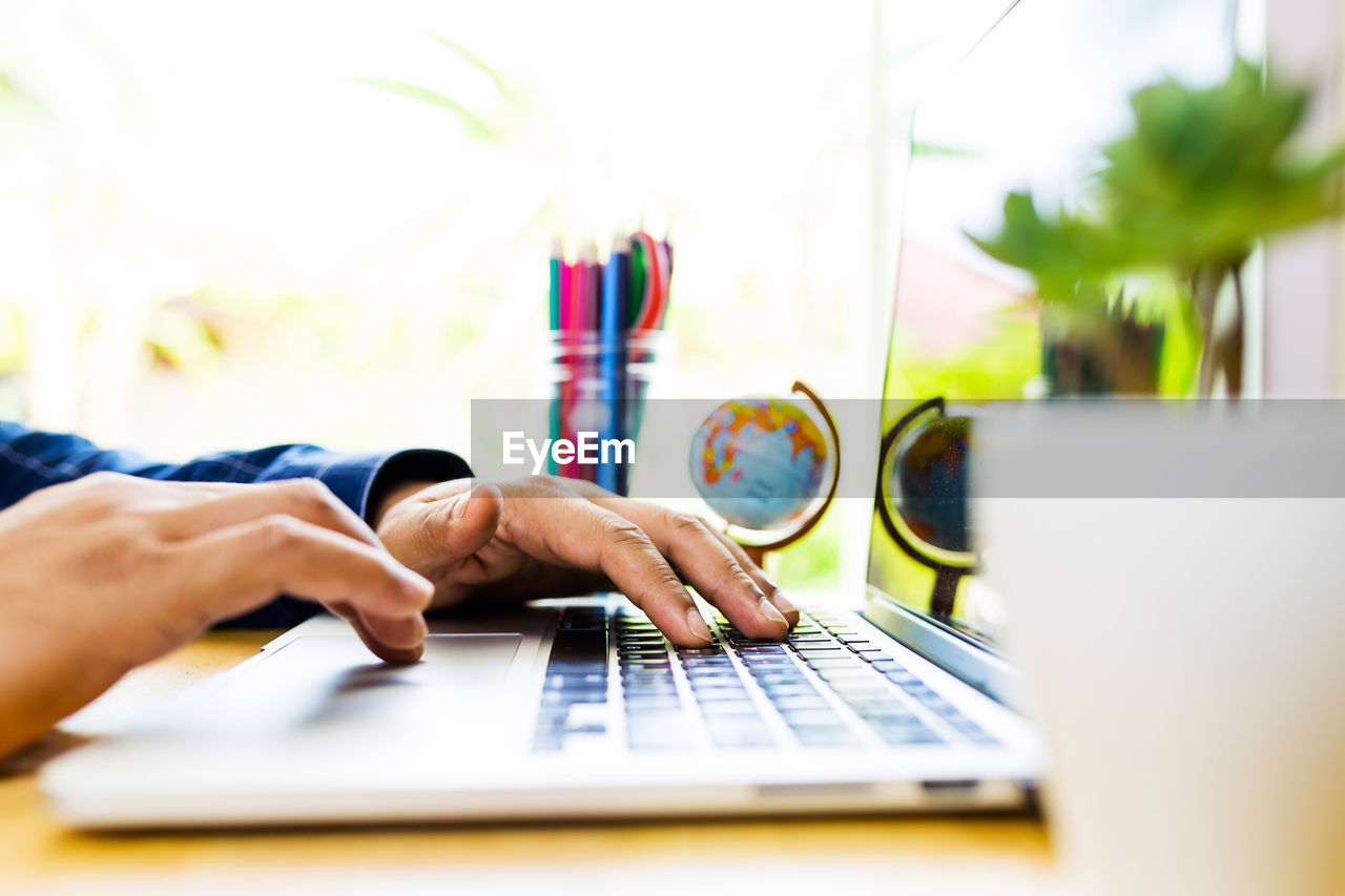 MIDSECTION OF WOMAN WORKING WITH LAPTOP