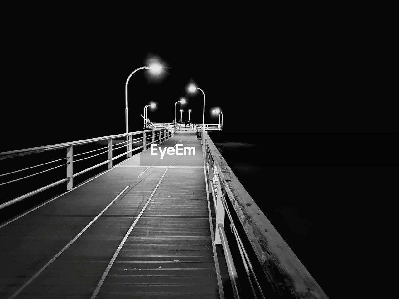 BRIDGE OVER ILLUMINATED FOOTBRIDGE AT NIGHT