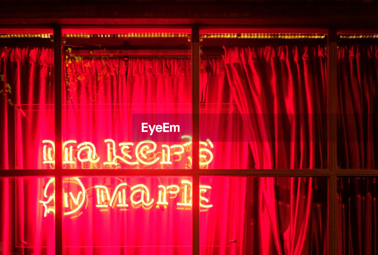 CLOSE-UP OF ILLUMINATED RED TEXT AT NIGHT