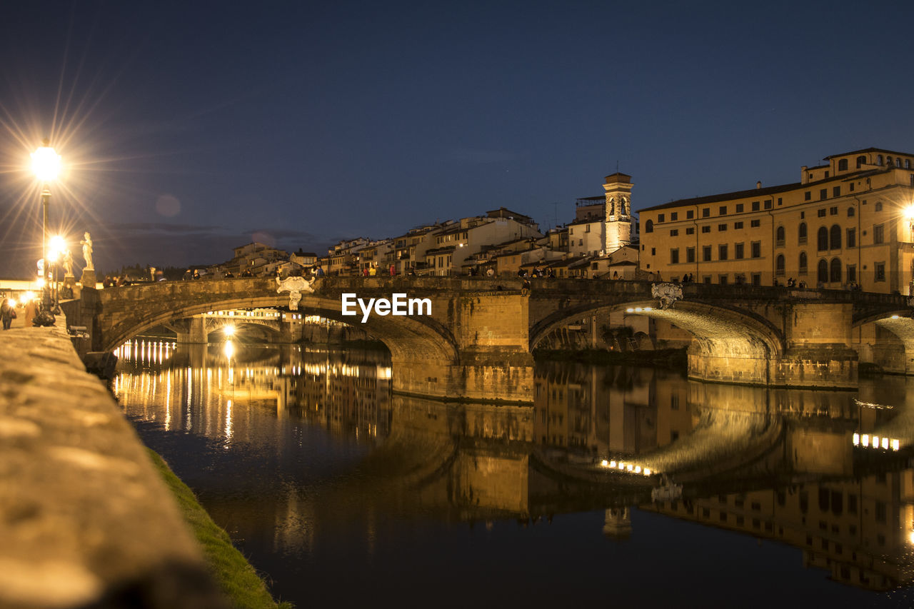 Arch bridge over river at night