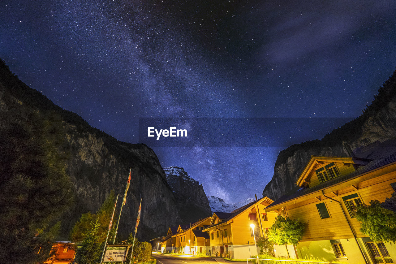 Illuminated houses against mountains at night