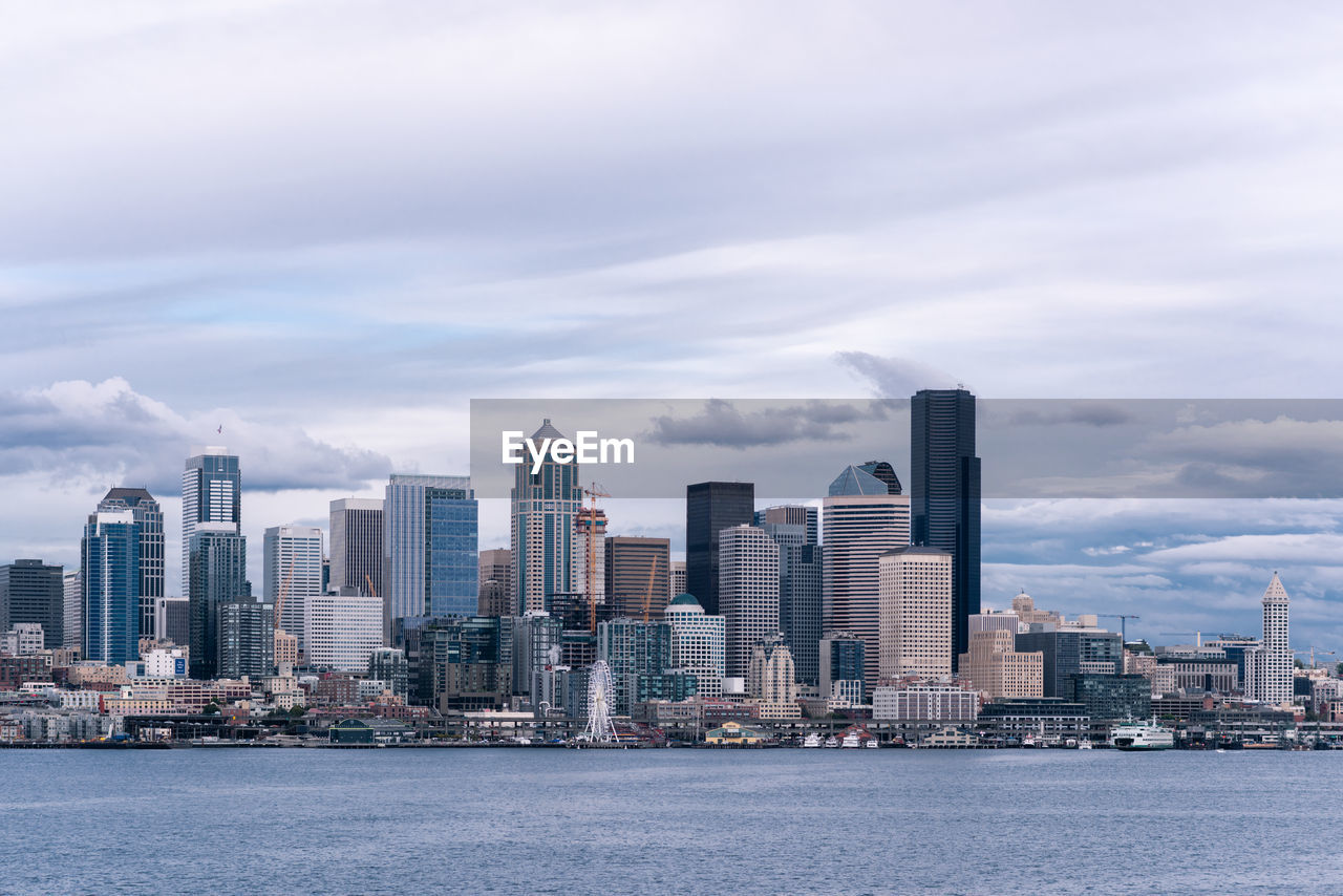 Sea by modern buildings against sky in city