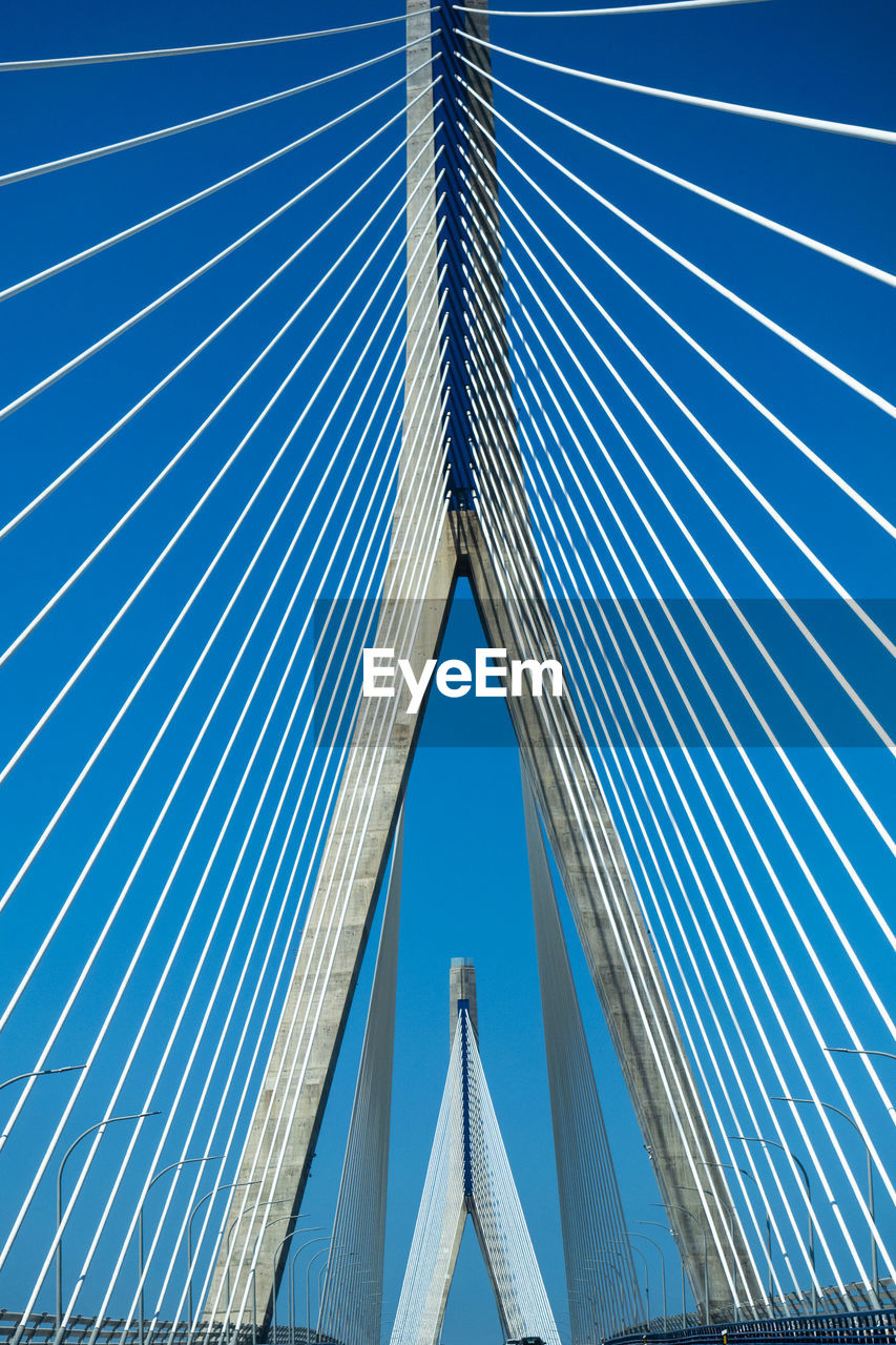 Low angle view of suspension bridge against blue sky