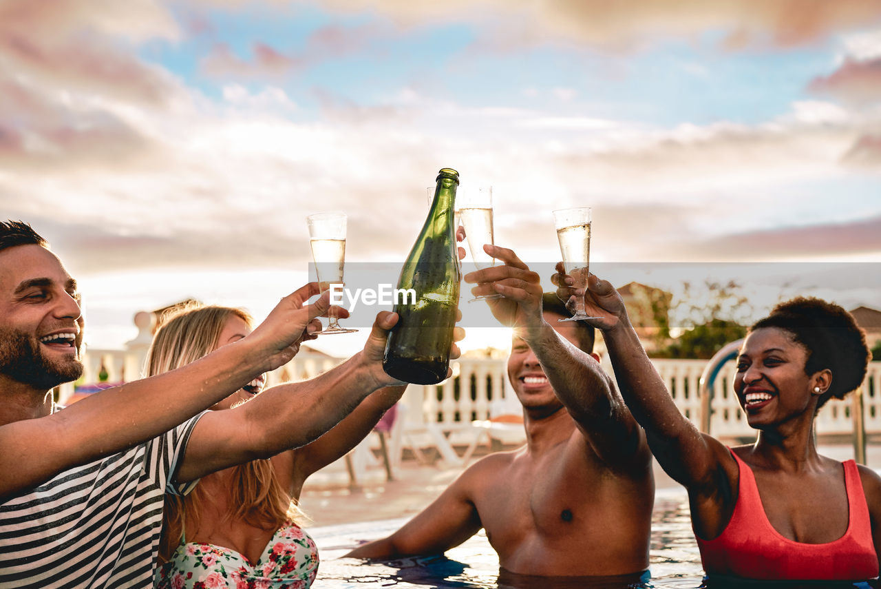 Friends toasting champagne flute in swimming pool