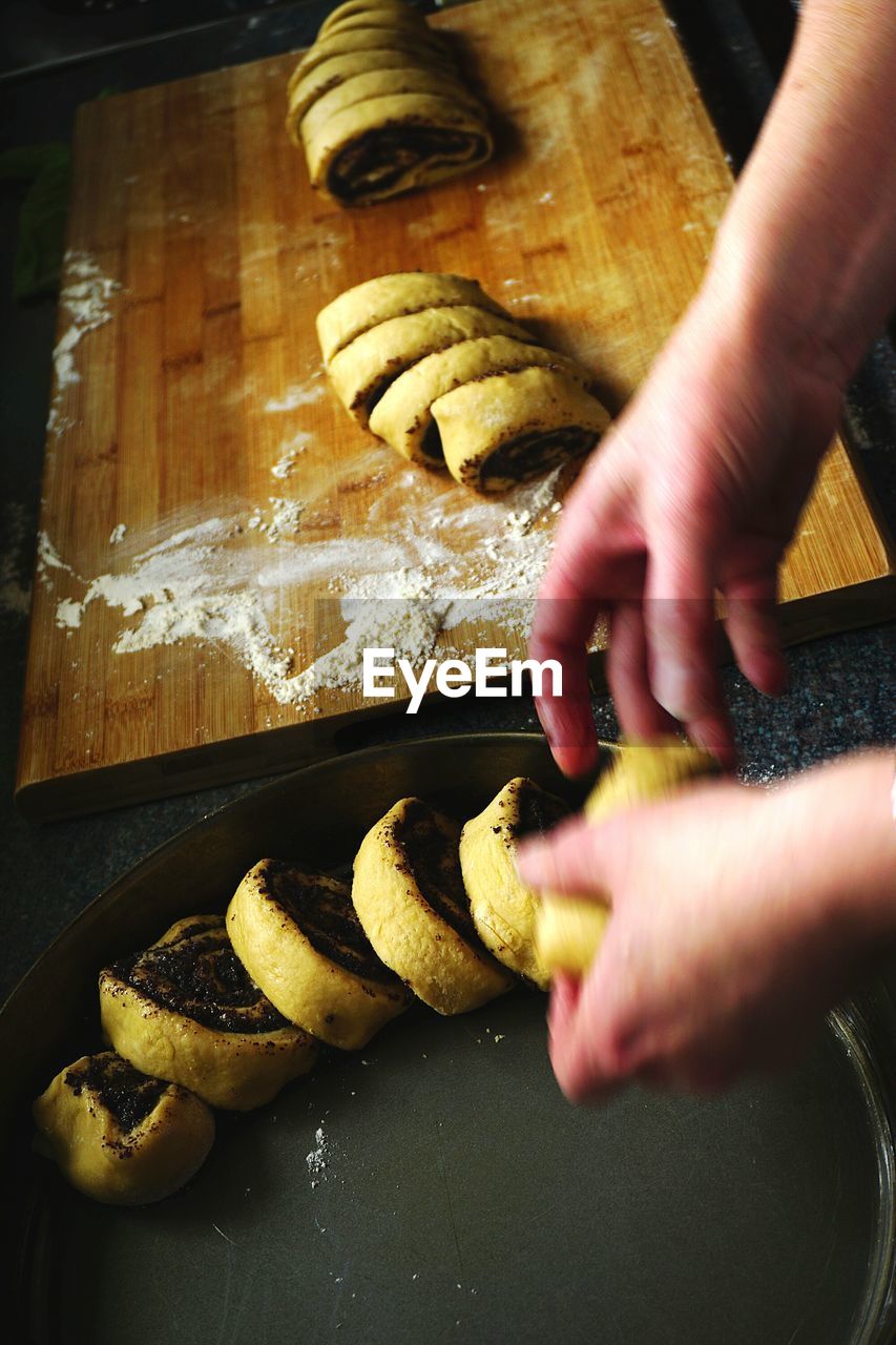 Cropped image of person arranging poppy seed cake slices in container