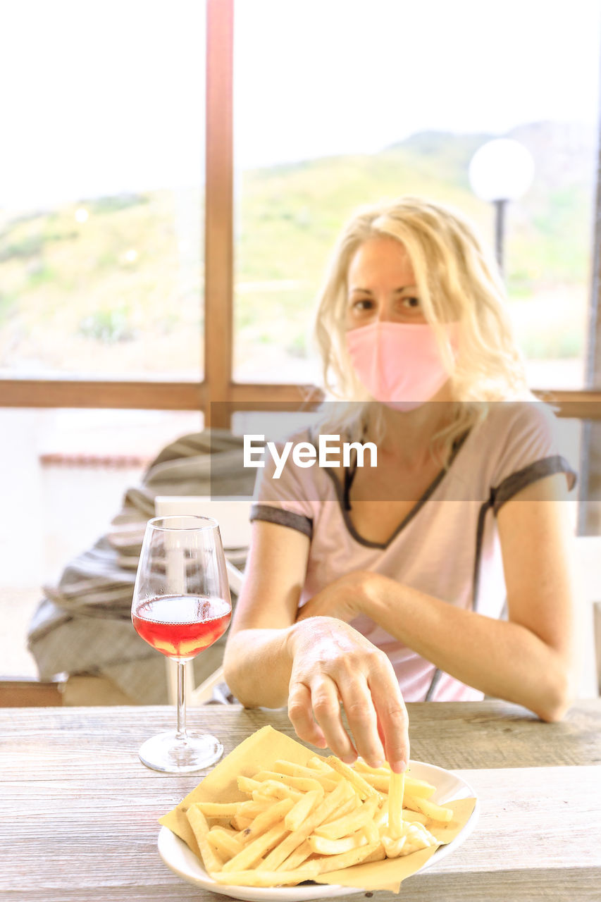 Portrait of smiling woman wearing mask sitting at restaurant