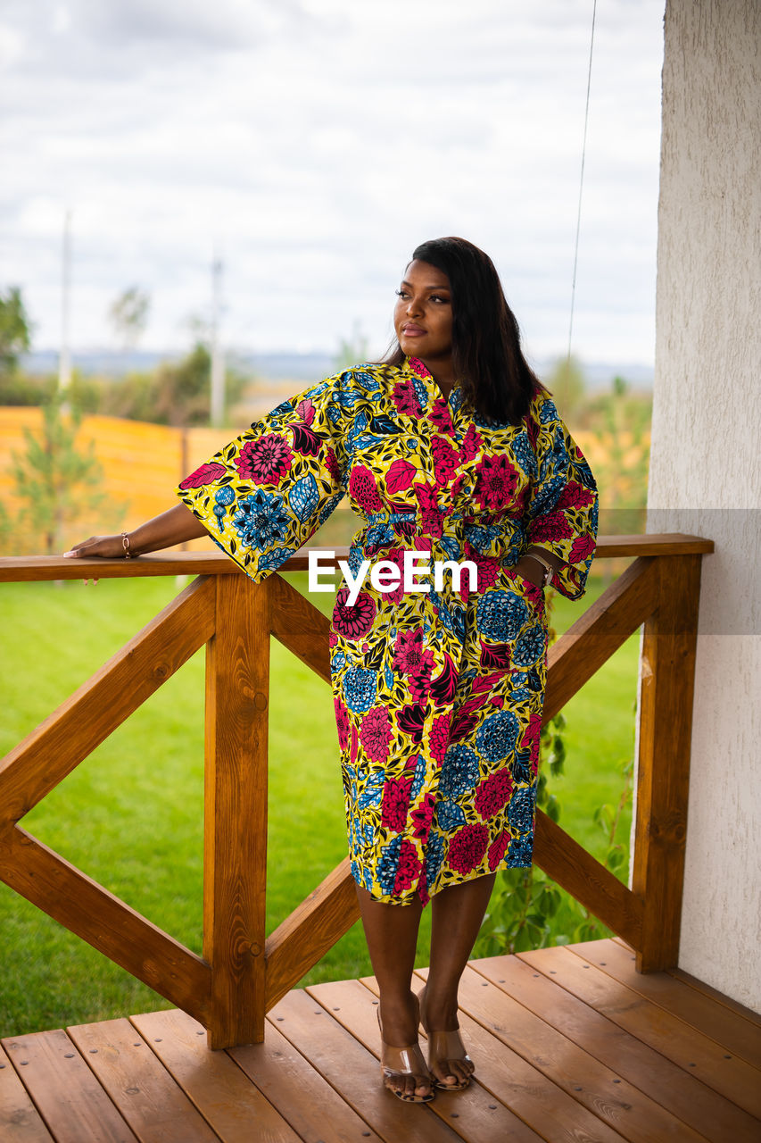 portrait of young woman standing on railing