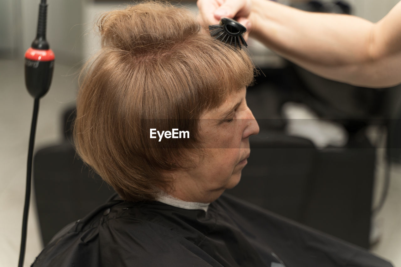 An elderly woman in a beauty salon does her hair