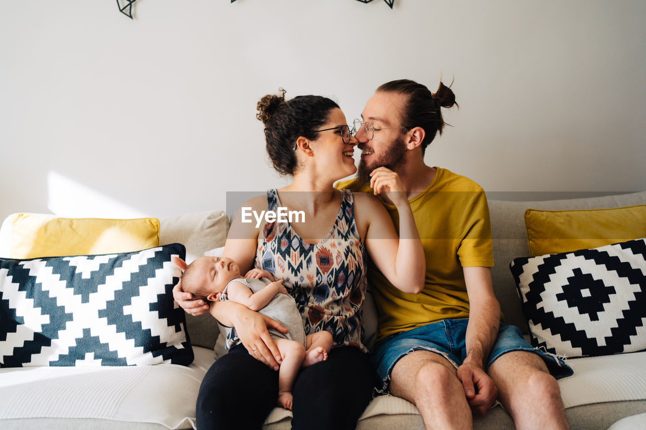 High angle view of young parents with their baby relaxing at home looking at new born