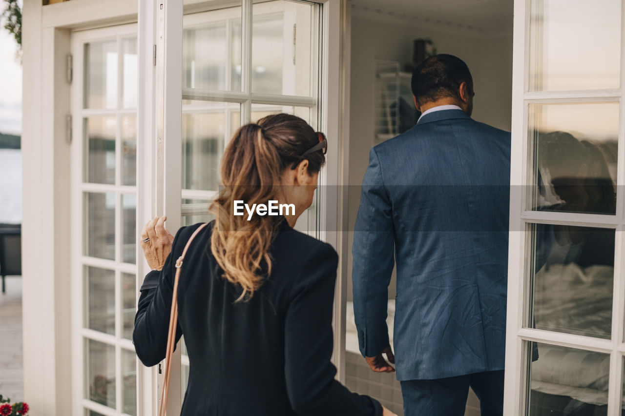 Rear view of mature couple entering holiday villa