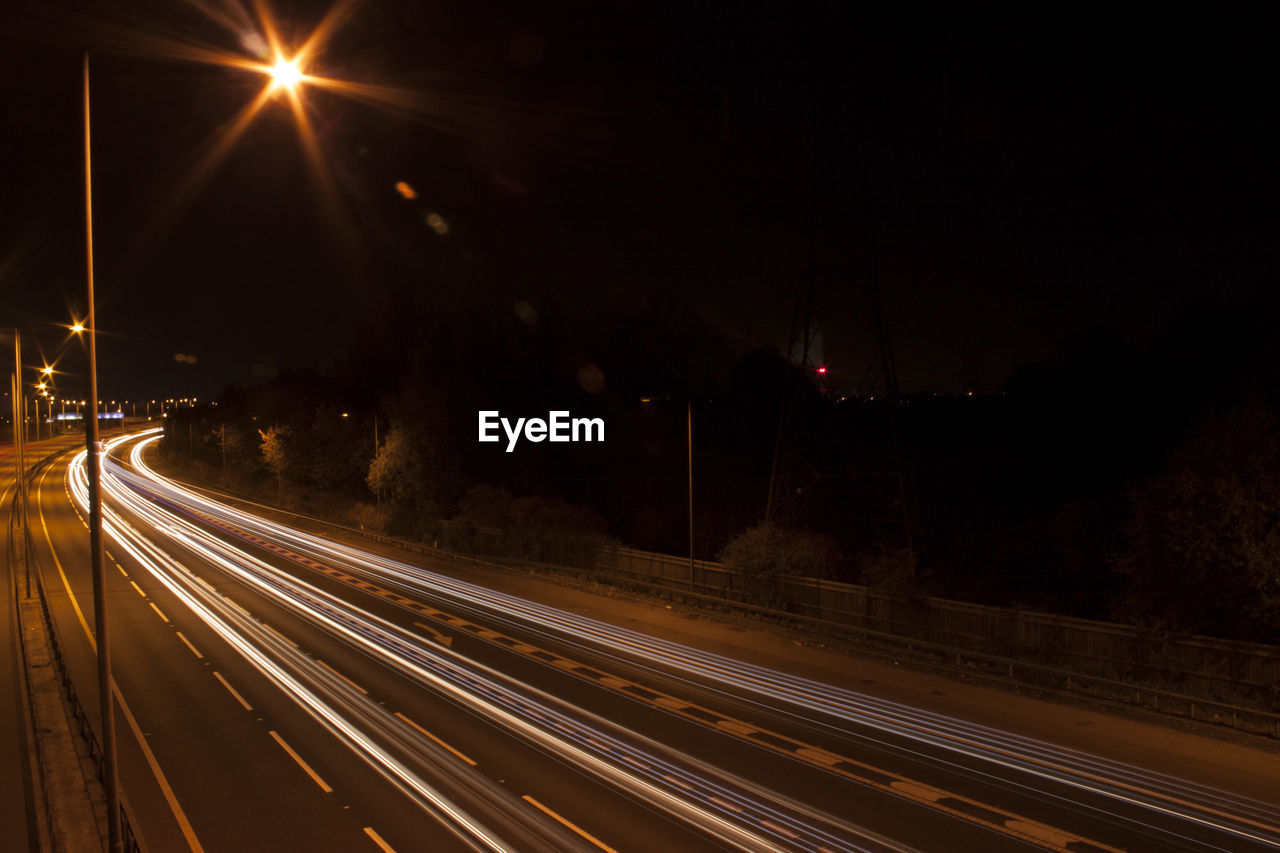 Light trails on road against sky at night