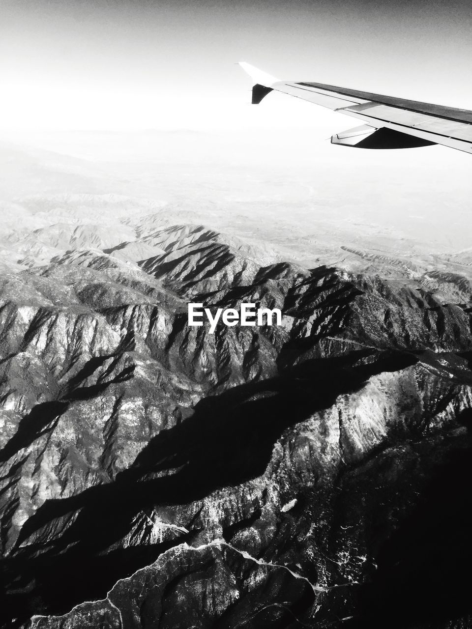 Cropped image of airplane flying over rocky mountains