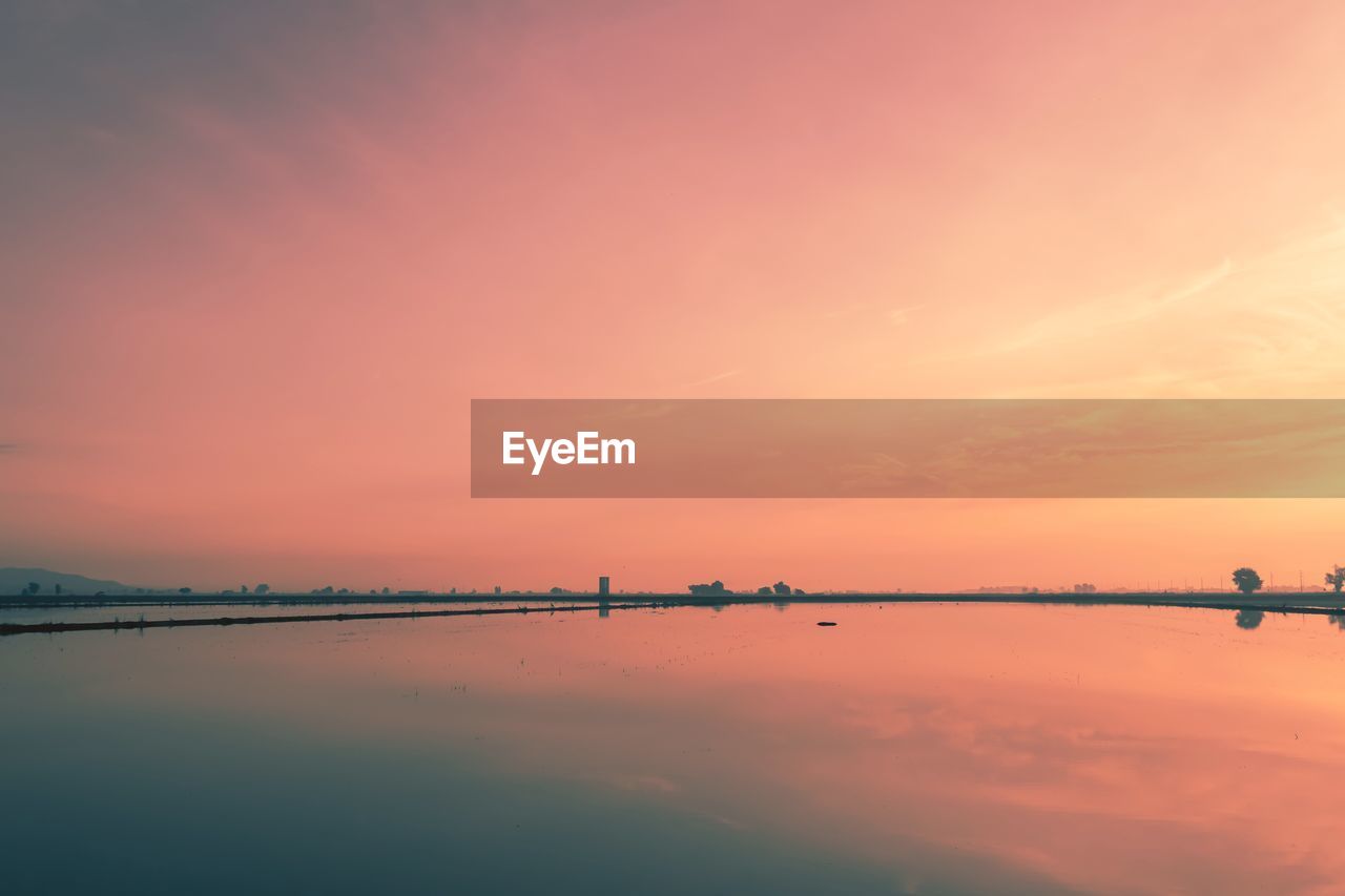 SCENIC VIEW OF LAKE AGAINST ORANGE SKY