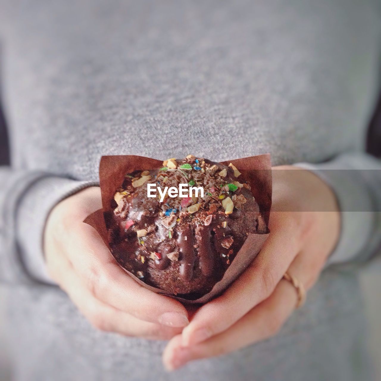 Midsection of woman holding chocolate muffin