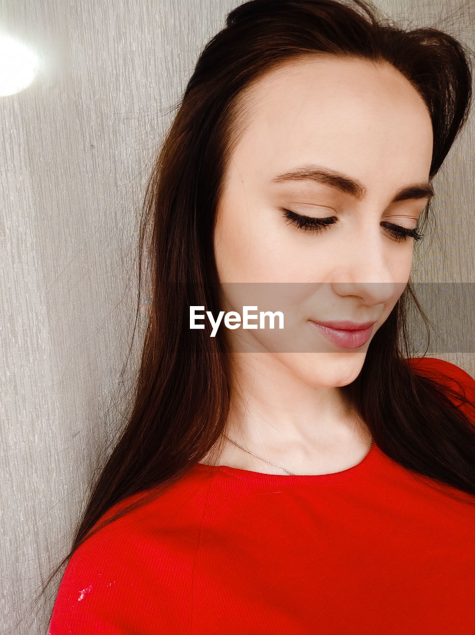 Close-up of smiling woman against wall