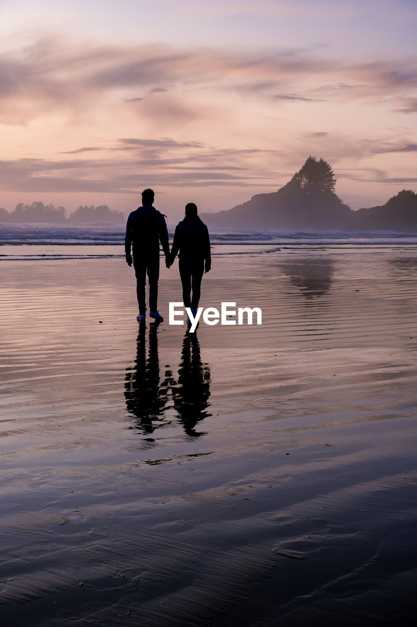 SILHOUETTE PEOPLE STANDING ON BEACH AGAINST SKY DURING SUNSET