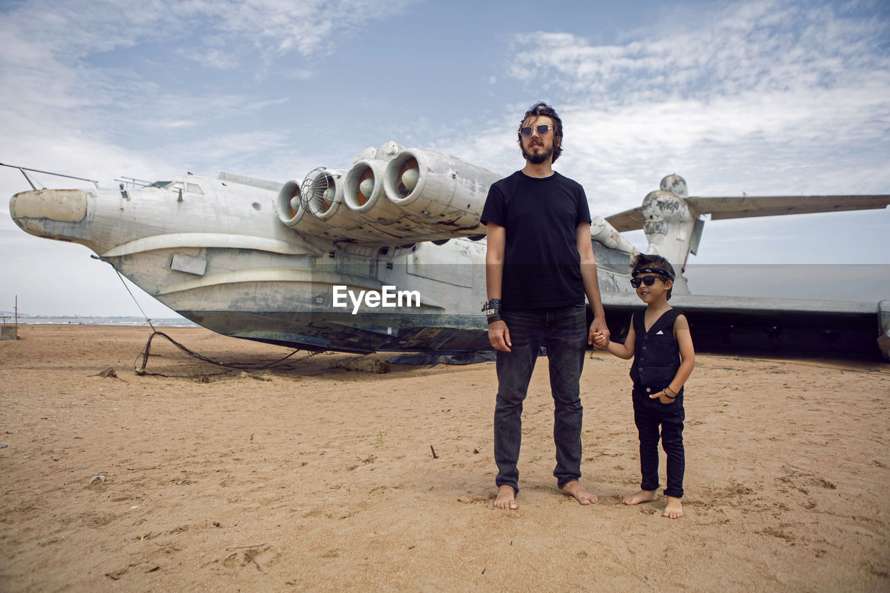 Family a boy and his father in rocker clothes stand ekranoplan plane by the sea in dagestan