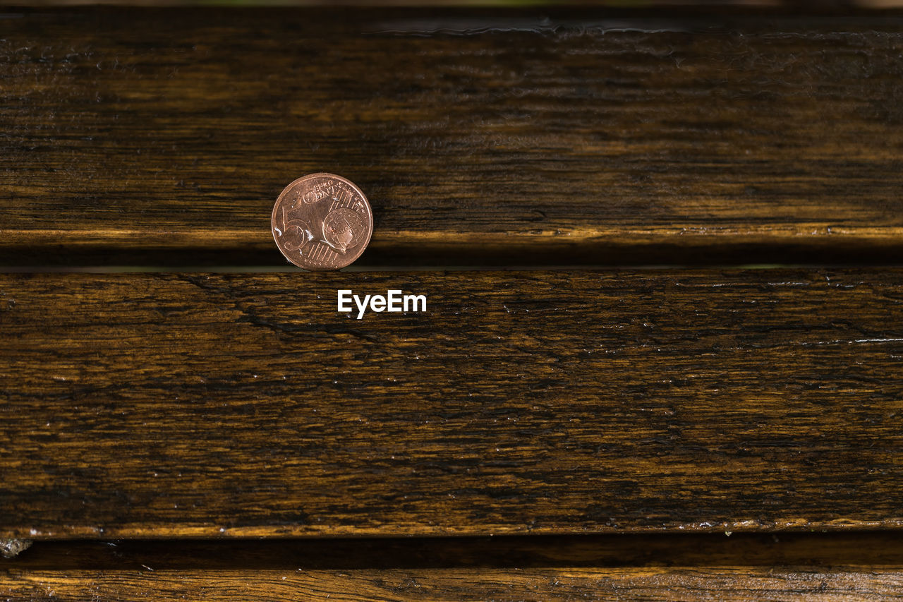 5 eurocent on a wooden bench at a rainy day.