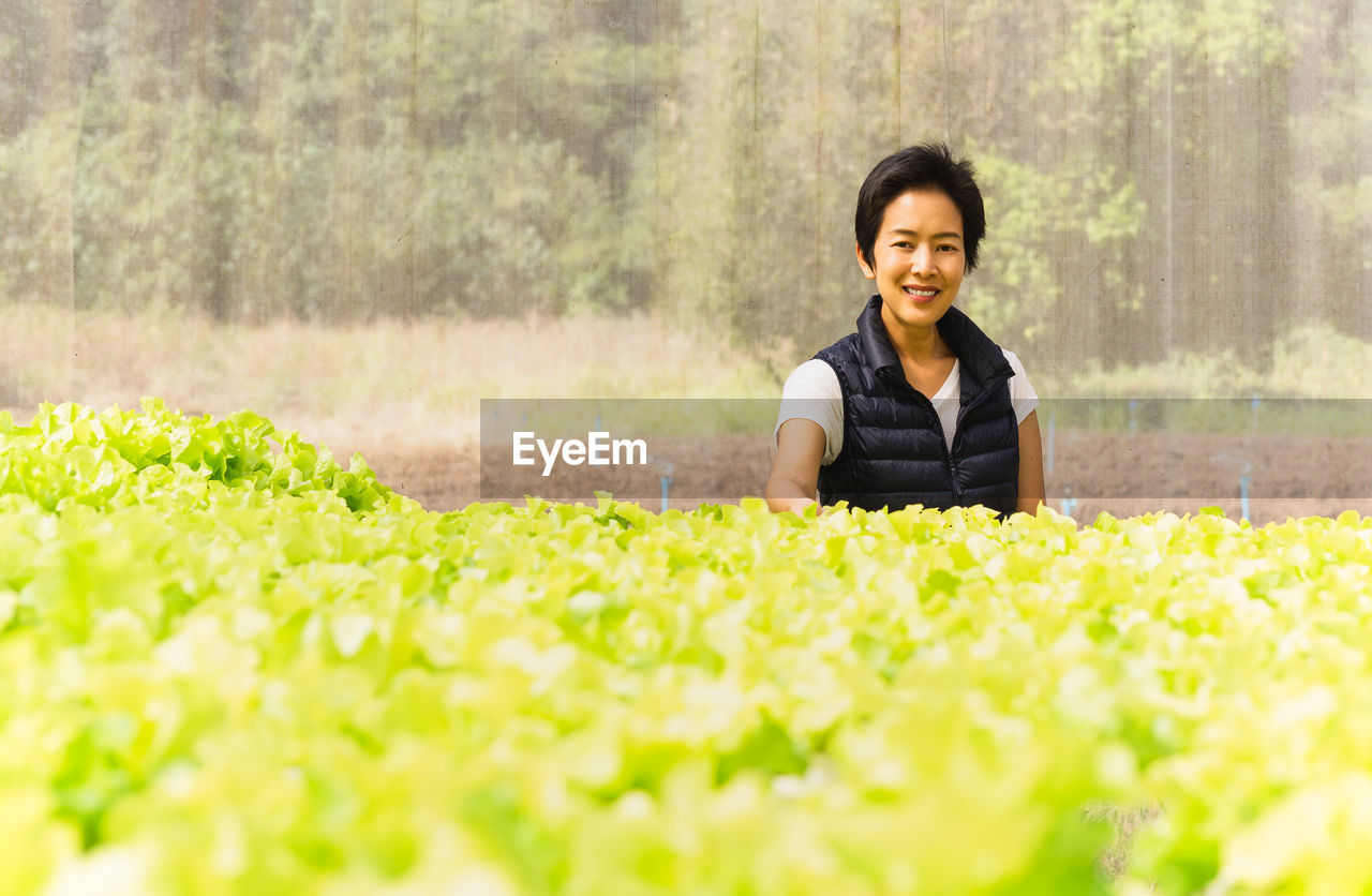 Happy woman farmer standing in hydroponic organic vegetable farm.