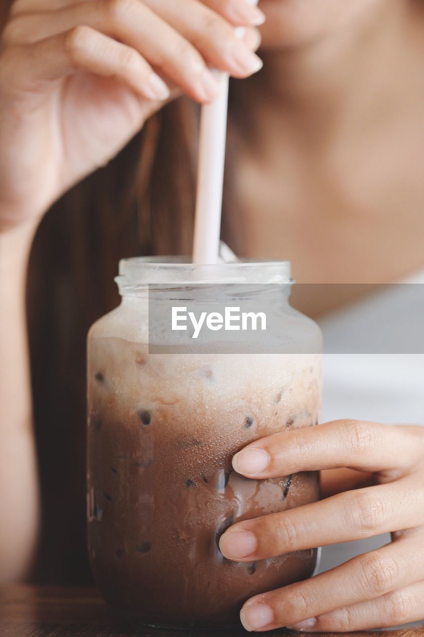 Midsection of woman having drink from jar