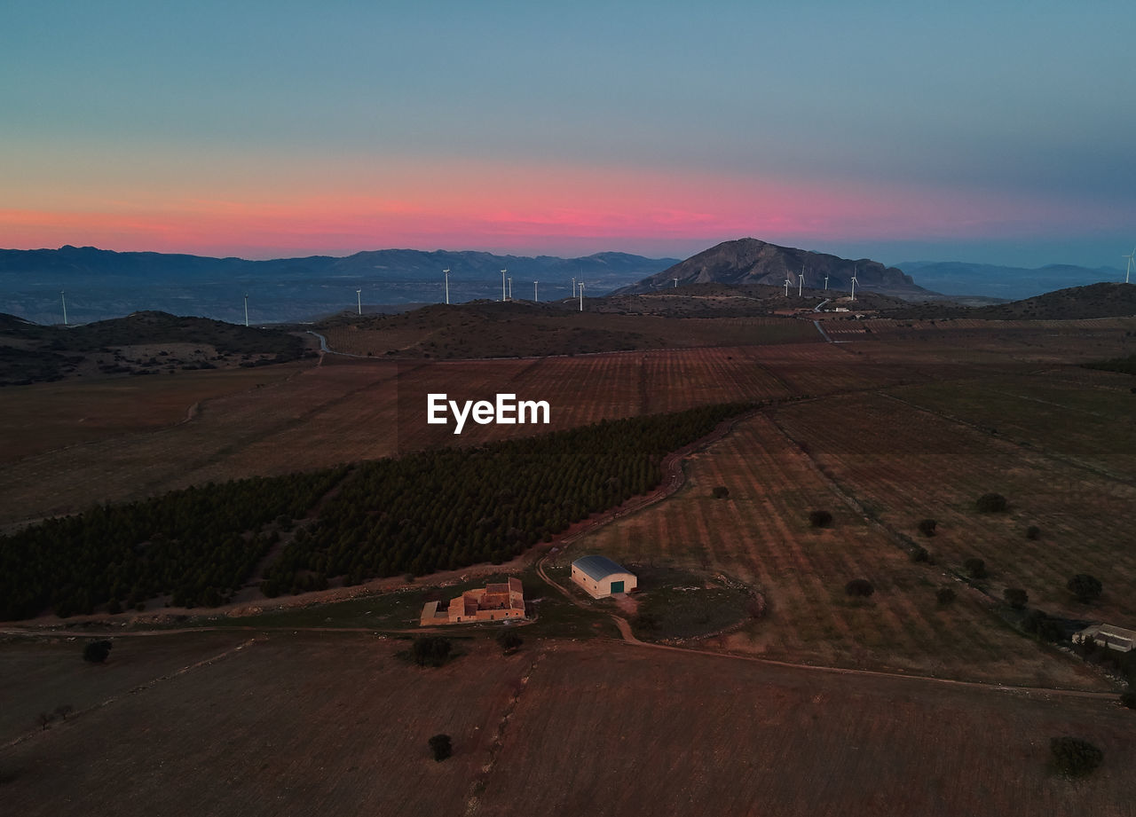 PANORAMIC VIEW OF AGRICULTURAL FIELD AGAINST SKY DURING SUNSET
