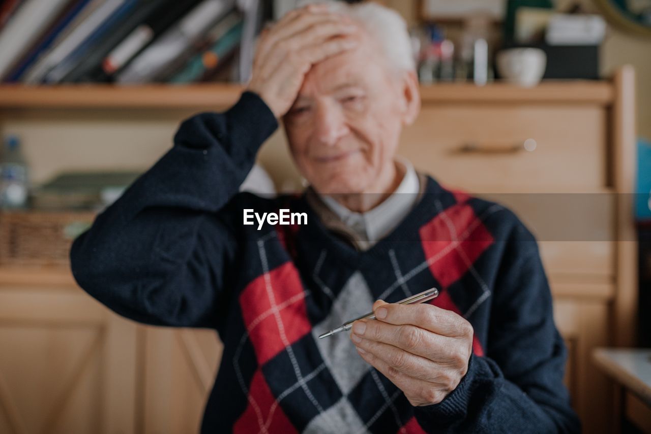 Midsection of man holding camera at home