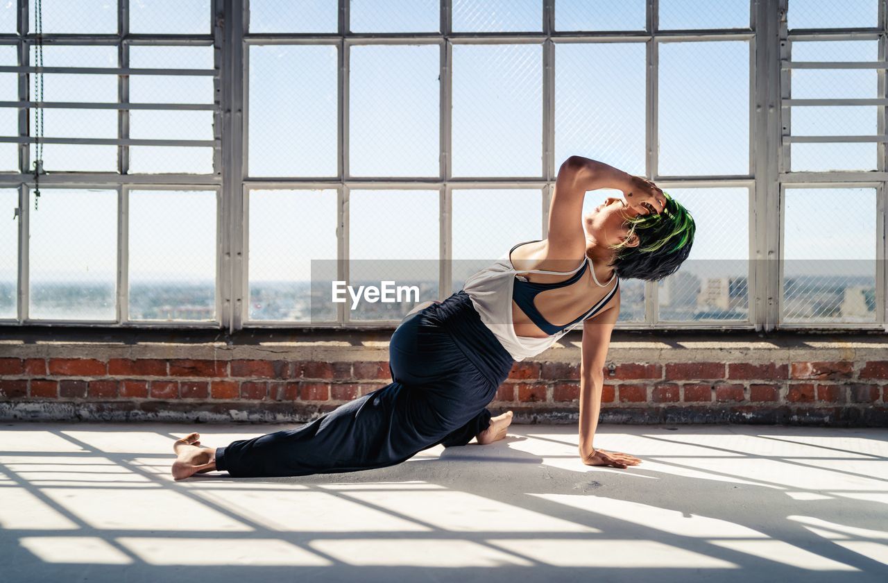 Full length of woman exercising by window