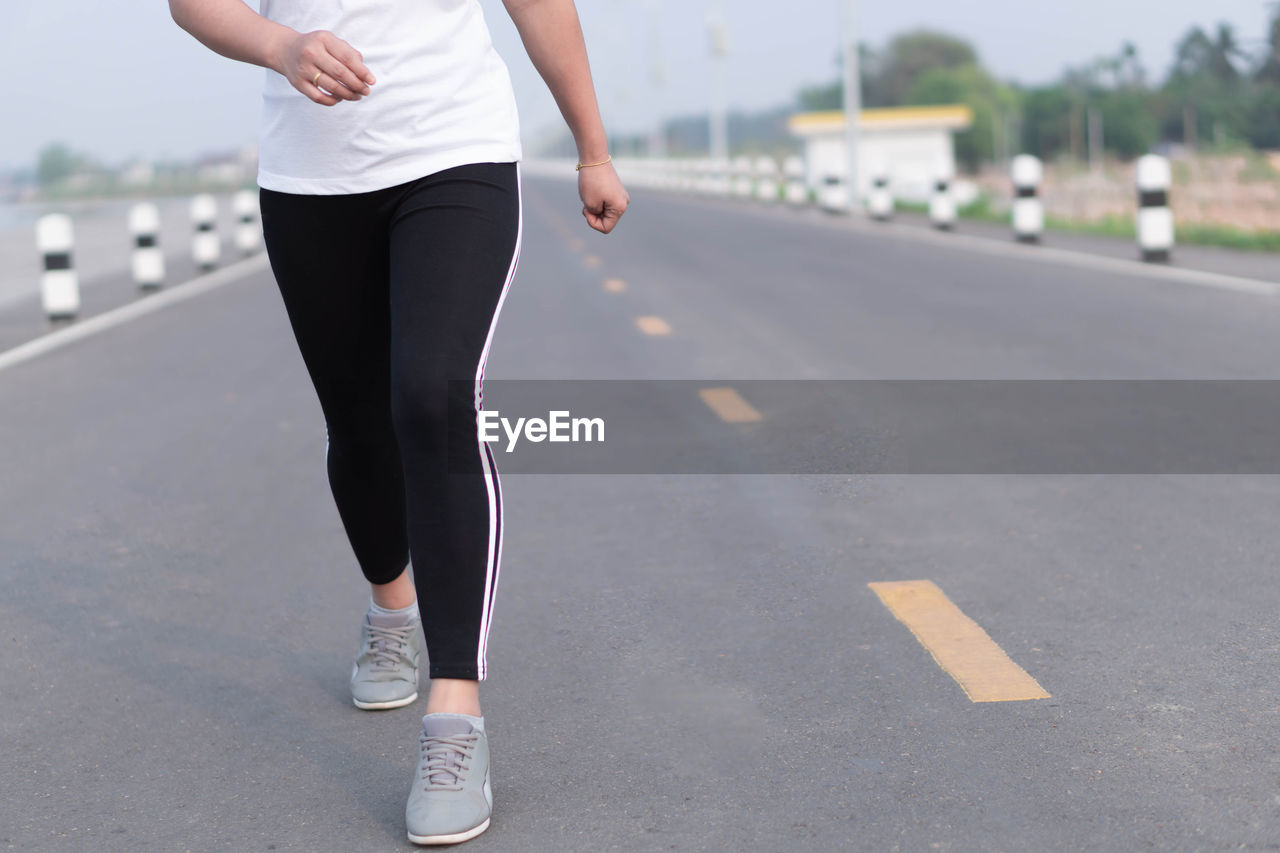 LOW SECTION OF WOMAN ON ROAD