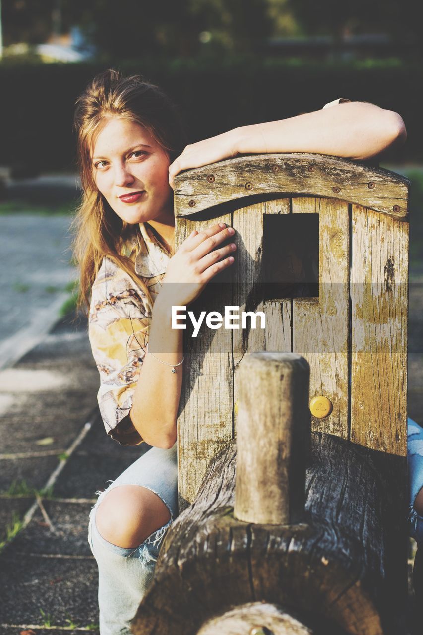 Young woman sitting on tree trunk