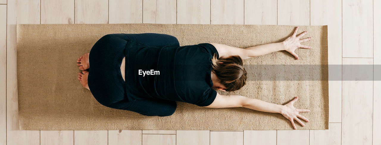 rear view of woman sitting on hardwood floor at home