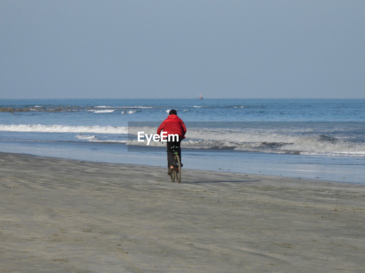 REAR VIEW OF WOMAN ON BEACH AGAINST SKY