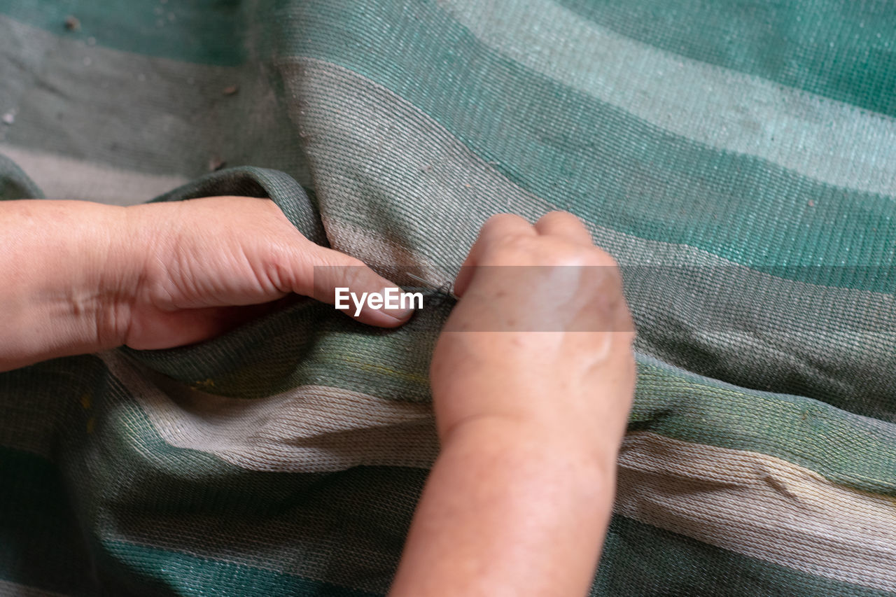 Cropped hands of woman stitching textile