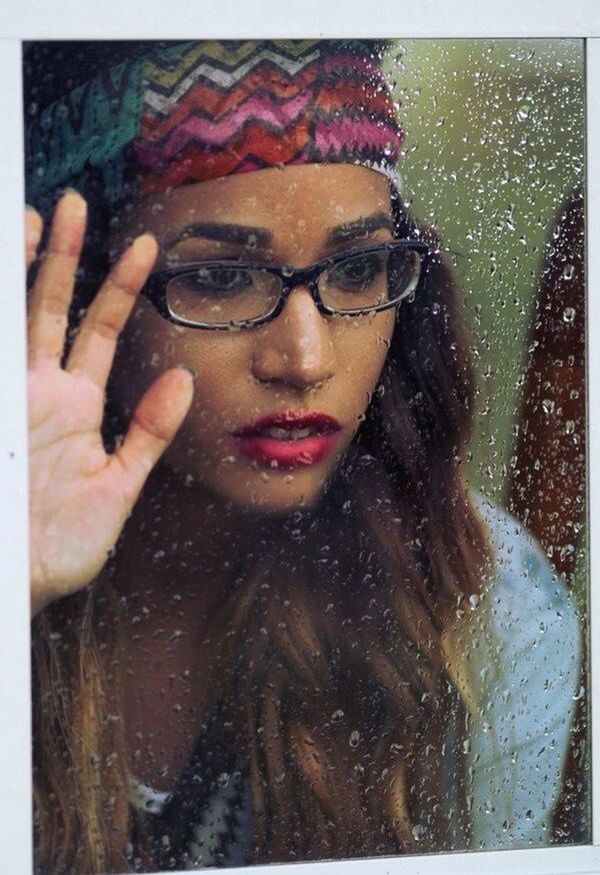 Close-up of young woman looking towards wet window