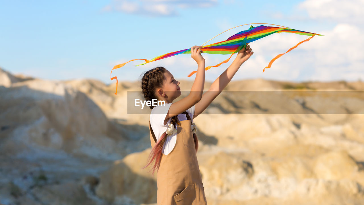 A girl of 8-9 years old launches a kite into the sky.